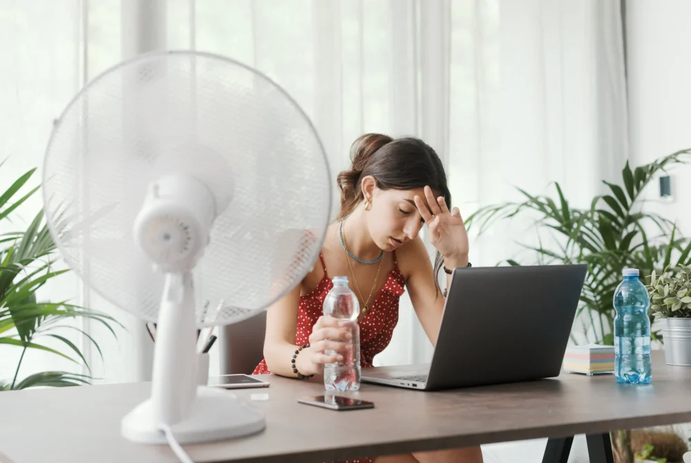 Forte chaleur au bureaux devant ordinateur, usage du ventilateur