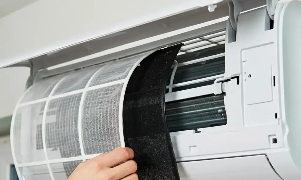 Technicien retirant le filtre d’une climatisation murale pour l’entretien ou le nettoyage de l’appareil.