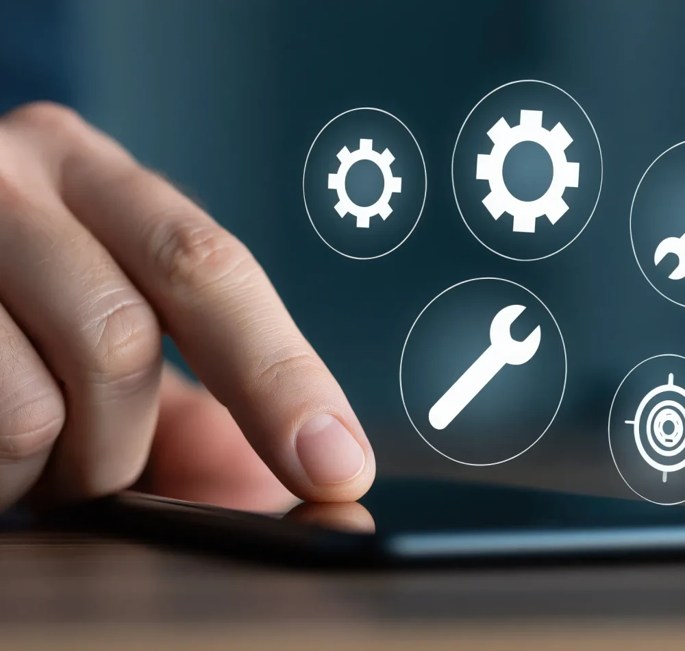 Main touchant l'écran d'un smartphone d'où émergent des icônes d'outils, de paramétrage et de gestion de projet.